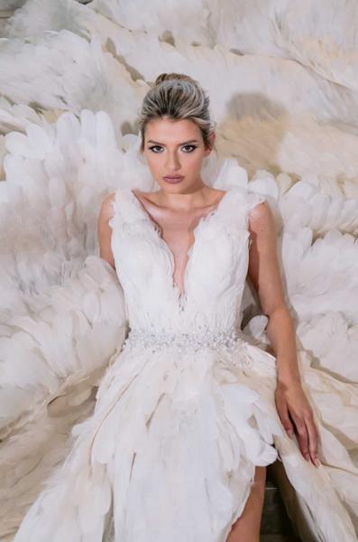Model in a white feathered bridal-style dress against a soft textured backdrop