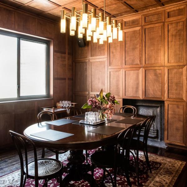 Wood-panelled meeting room with round table, chairs, flowers and pendant lighting