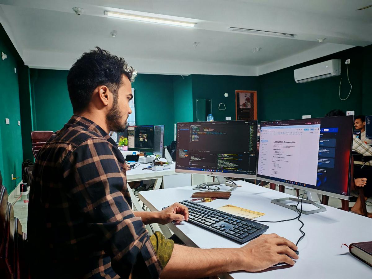 Web developer working at a desk with dual monitors showing code in a modern office